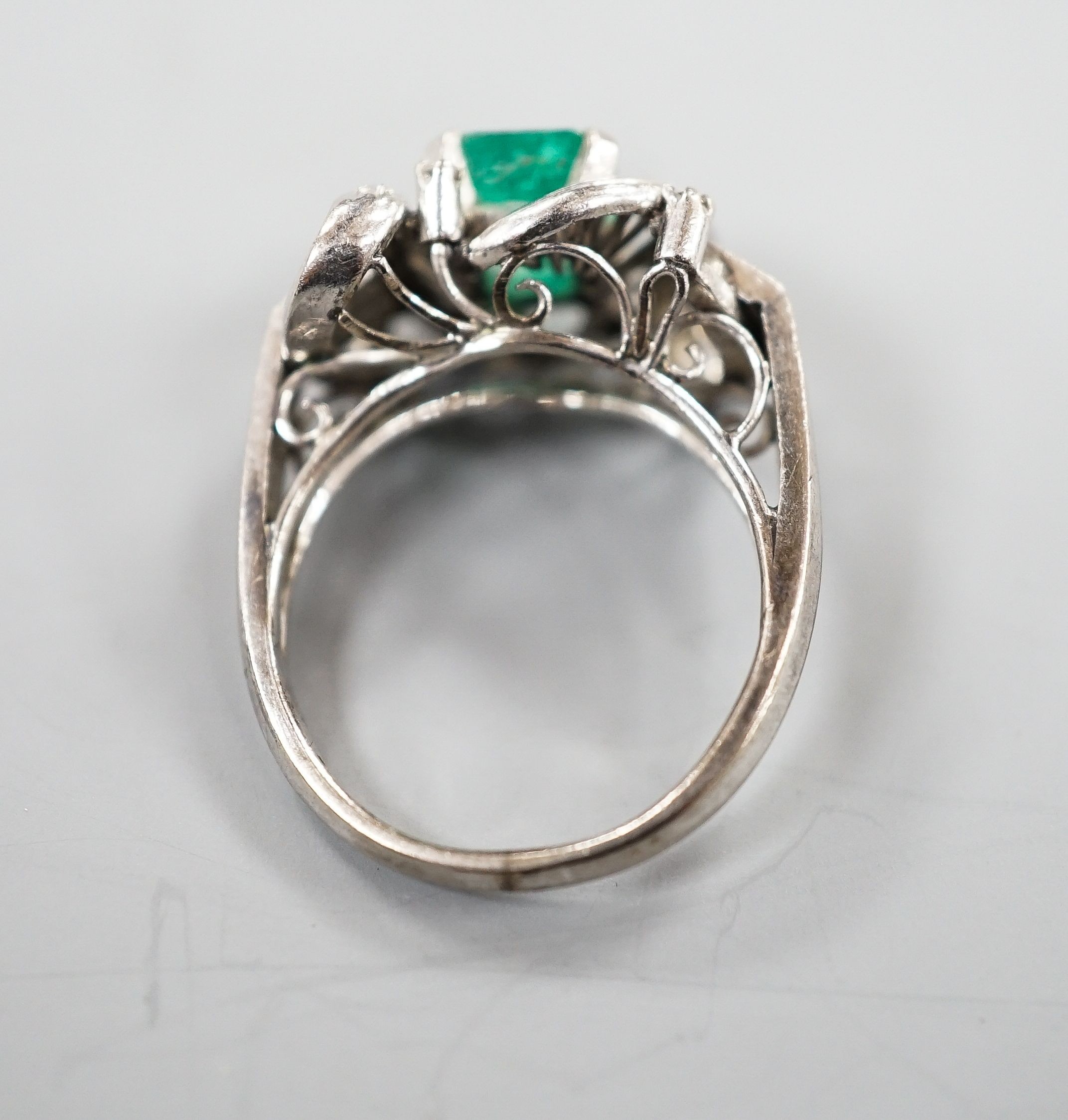 A modern 14k white metal and single stone emerald ring, with diamond chip set scroll setting, size K/L, gross weight 4.5 grams.